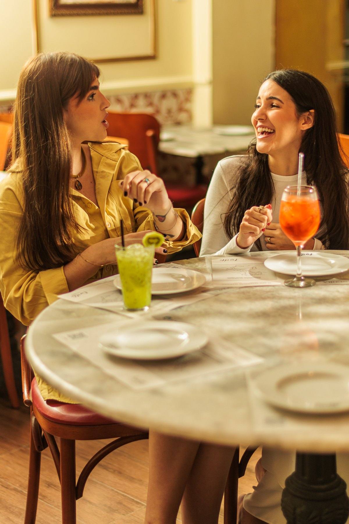Duas amigas conversando em uma mesa de mármore no salão